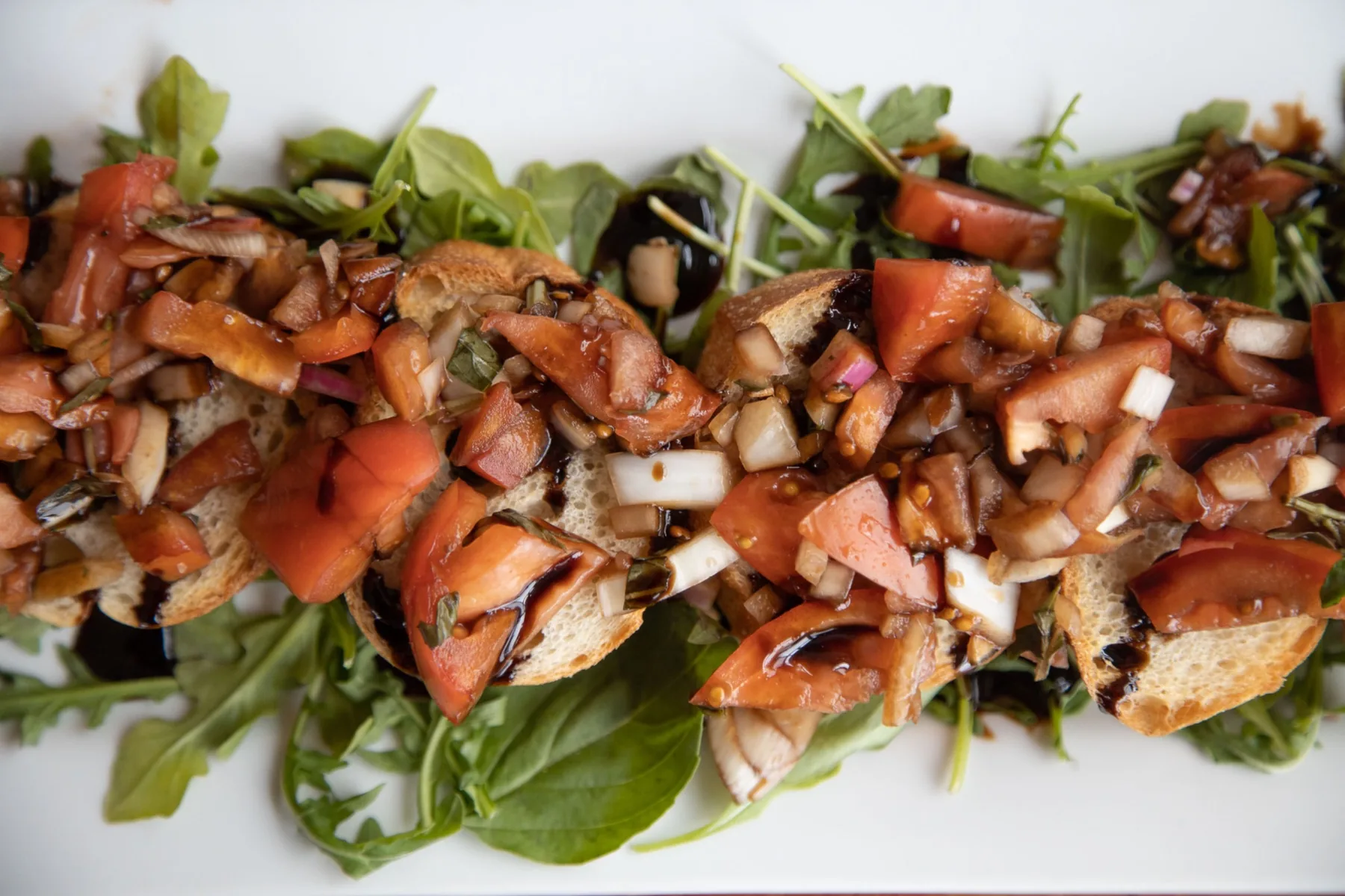 Commercial food photography of bruschetta topped with tomatoes and herbs