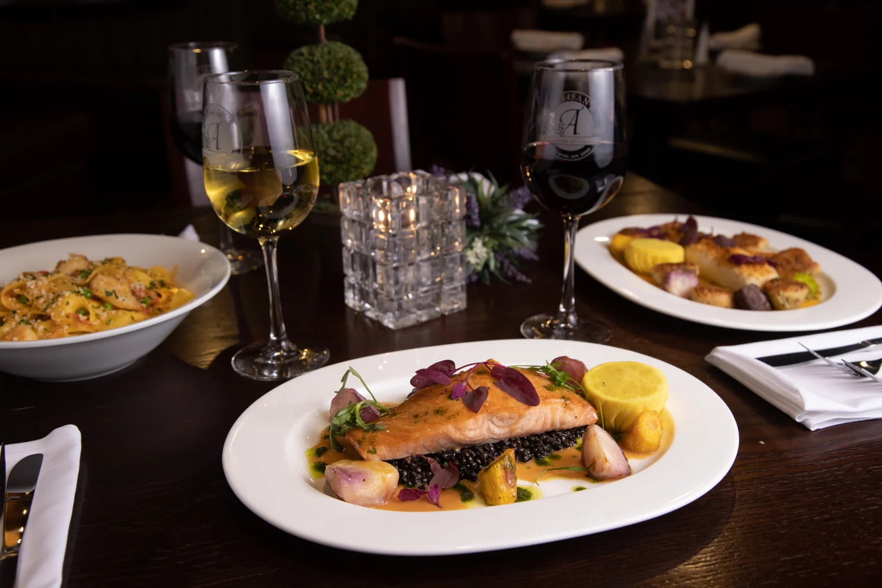 Commercial food photography of a plated salmon entrée with vegetables and restaurant table setting